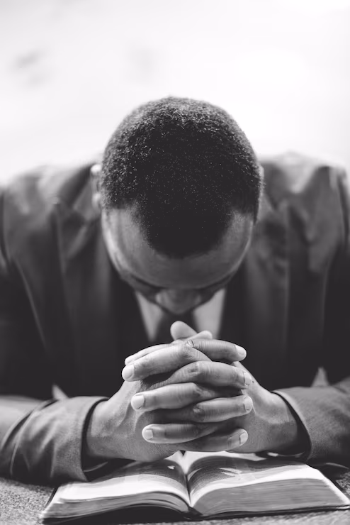 lonely african american male praying with his hands bible with his head down 181624 19796